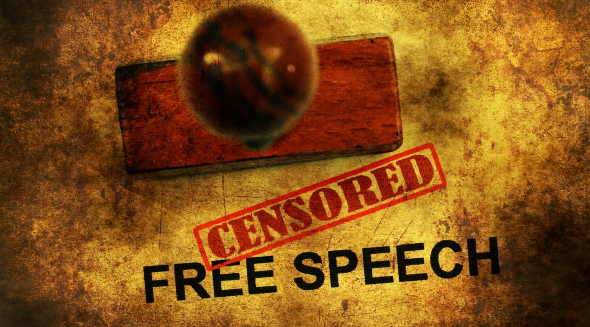 The words 'FREE SPEECH' are stamped on a textured surface, with a red 'CENSORED' stamp placed over them, symbolizing the conflict between free expression and censorship.