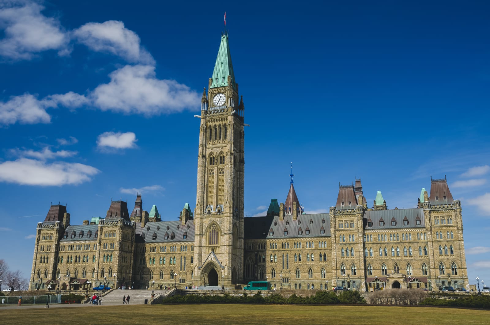 The Centre Block of the Canadian Parliament Buildings in Ottawa on a sunny day, with the Peace Tower prominent against a blue sky with white clouds.