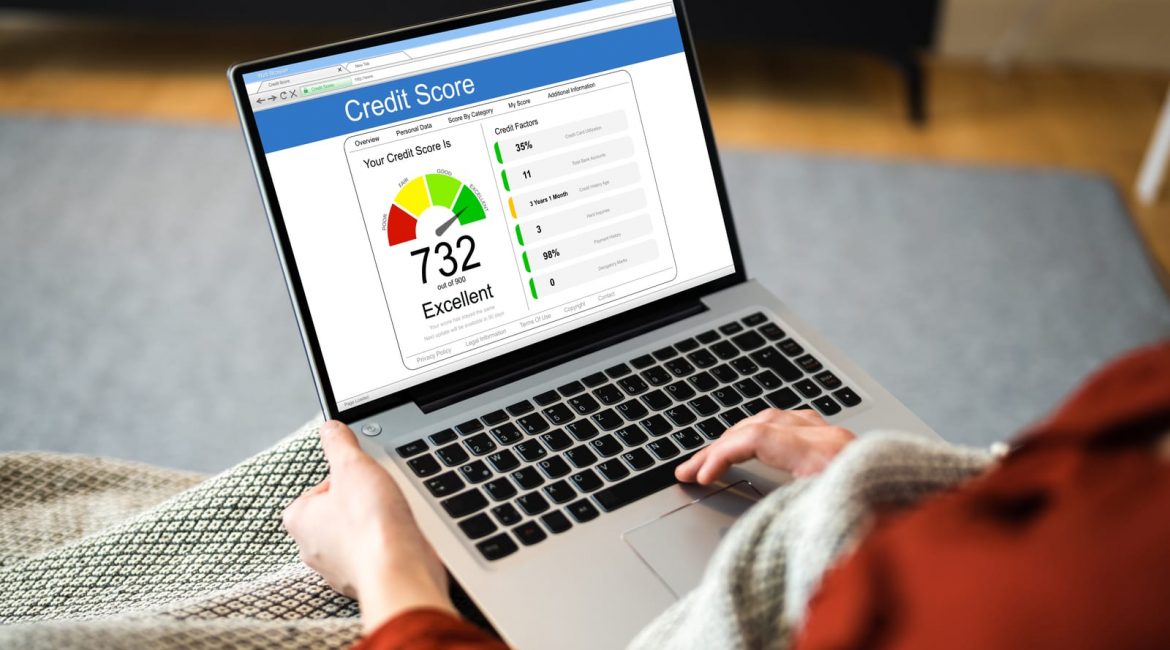 A person sitting with a laptop, looking at a website on the screen that shows an excellent credit score of 732 out of 900
