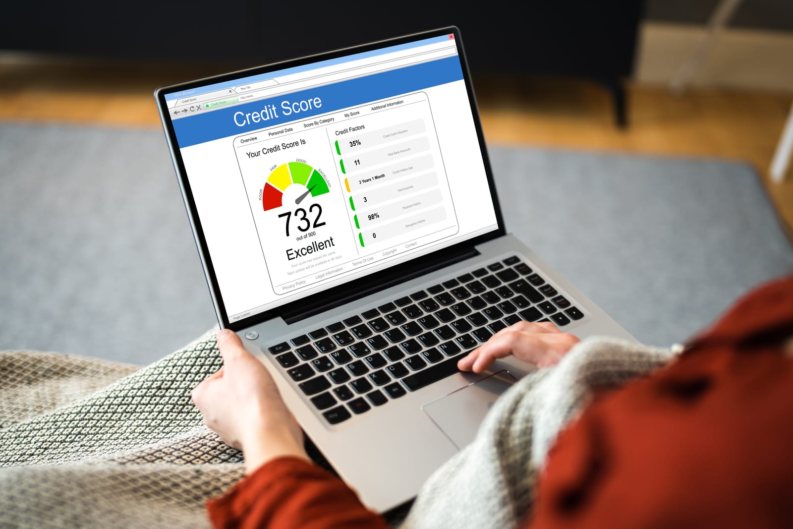 A person sitting with a laptop, looking at a website on the screen that shows an excellent credit score of 732 out of 900