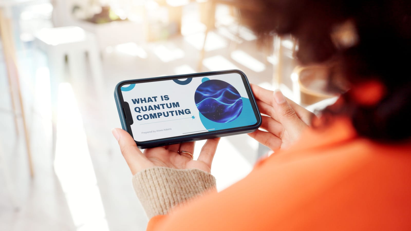 A person holds a smartphone displaying a presentation slide with the title 'What Is Quantum Computing,' representing a modern explanation of the topic.
